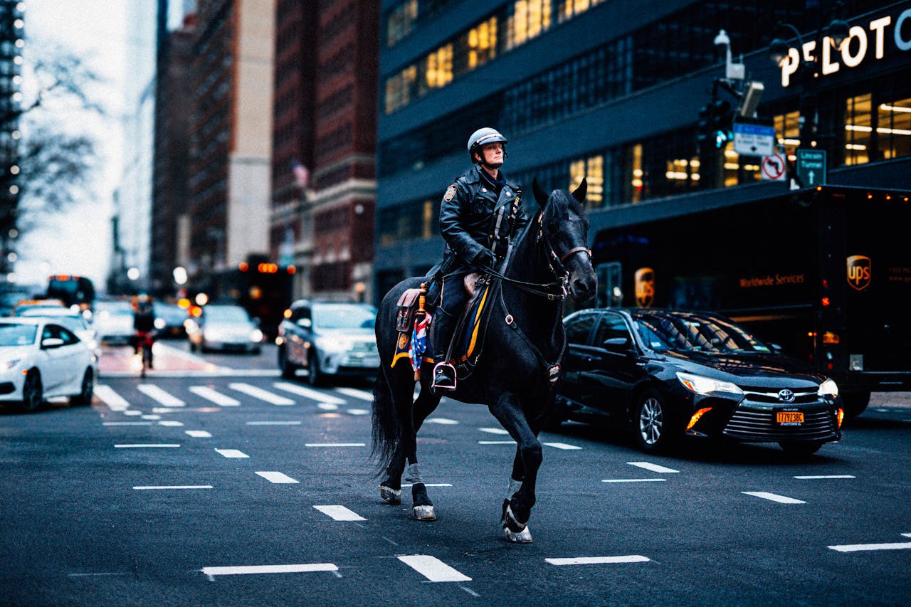 A mounted police officer patrolling a busy street in New York City during the day.